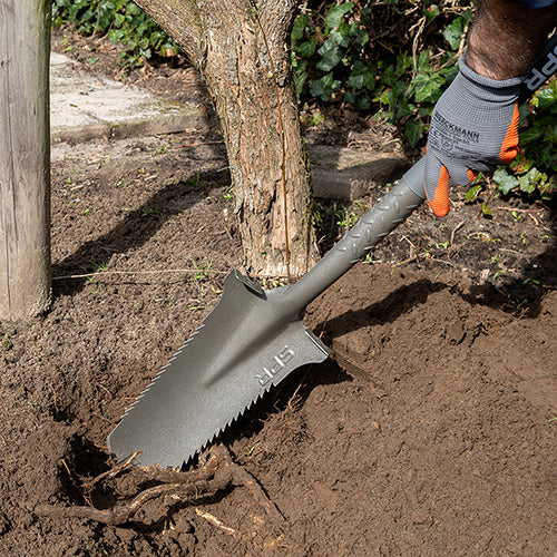 Zaagspade zaagt een wortel door in een plantgat bij een boom
