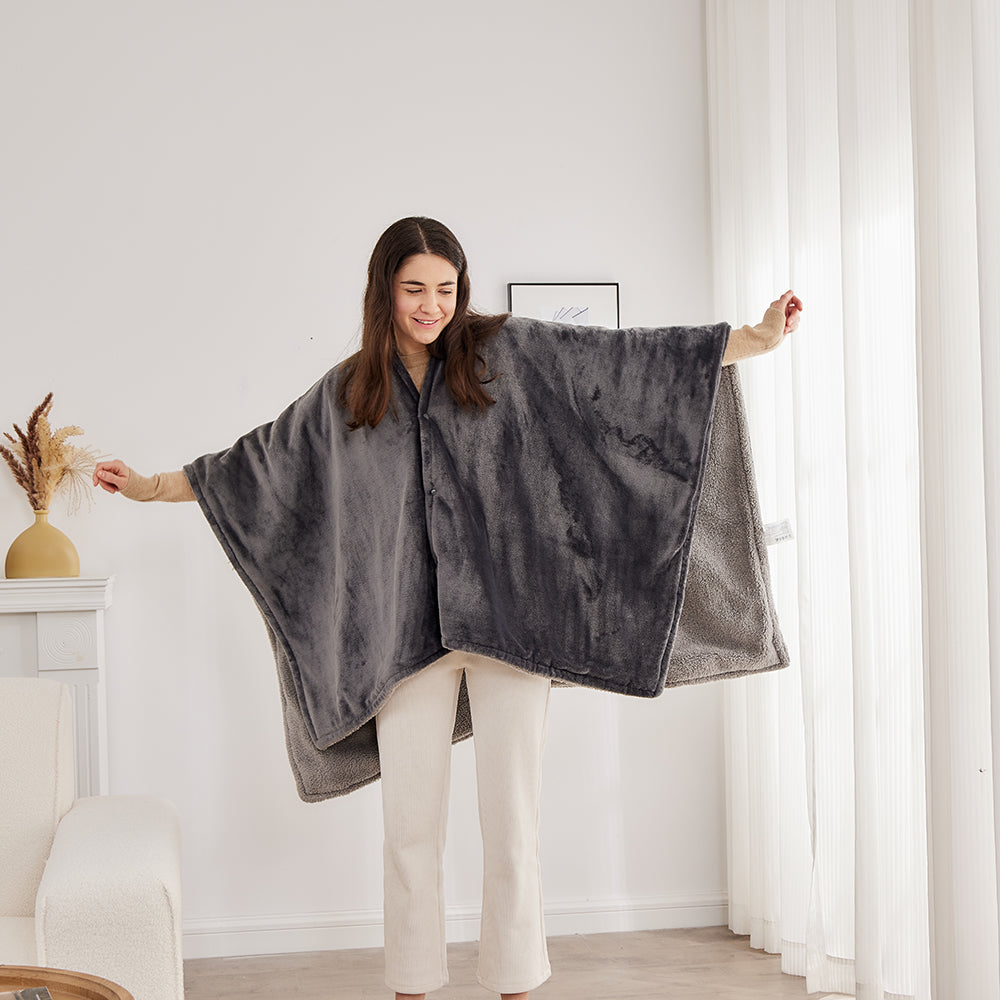 Vrouw toont het ruime formaat van de elektrische poncho met gespreide armen, vooraanzicht