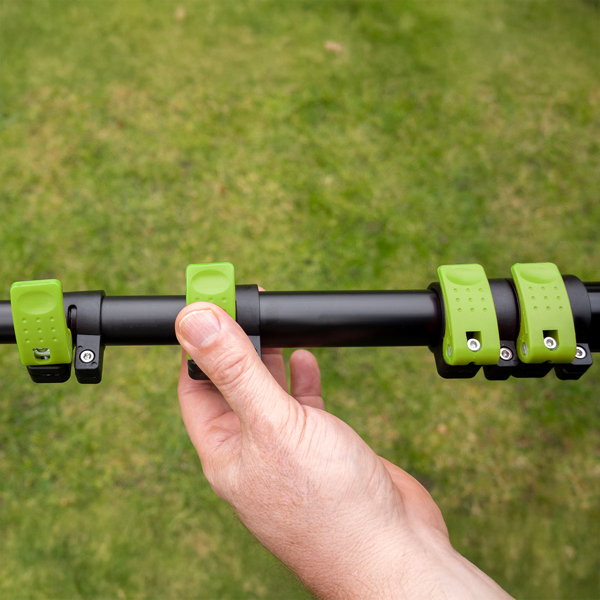 Hand opent een groene klem om de telescoopsteel uit te schuiven
