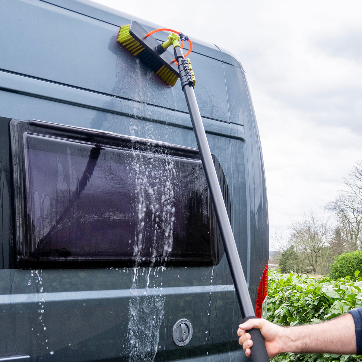 Camper wordt gewassen met de wasborstel waar water doorheen stroomt