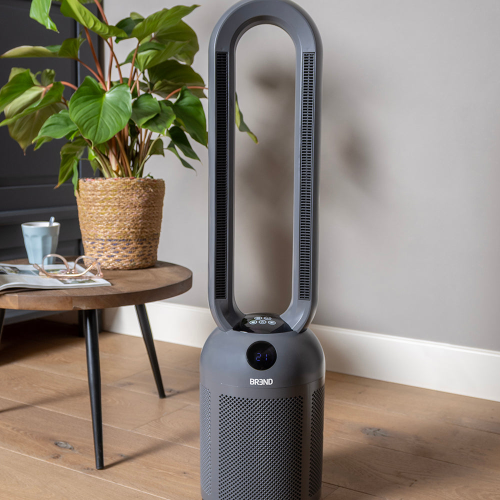 Chauffage soufflant sans pales gris dans un salon, à côté d'une table d'appoint avec une plante