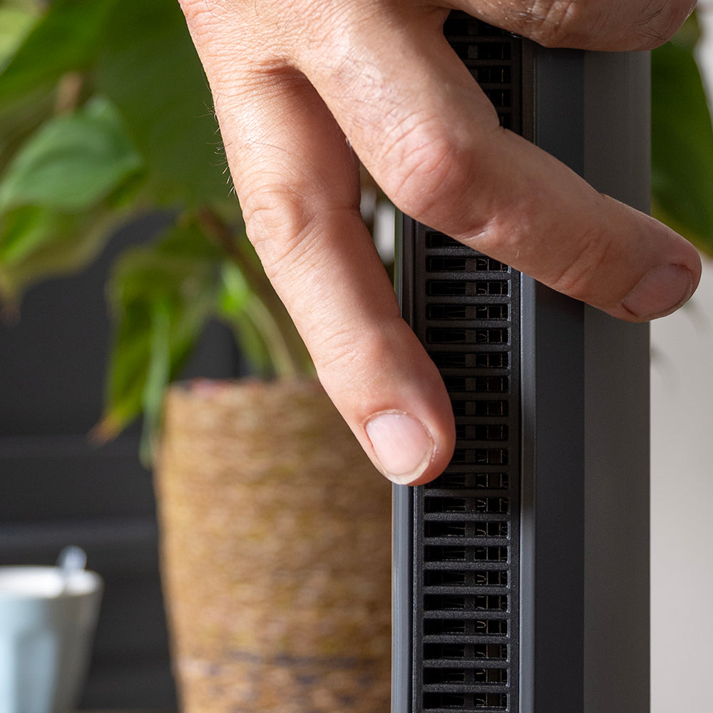 Une main sent le flux d'air à la grille de sortie du chauffage soufflant sans pales