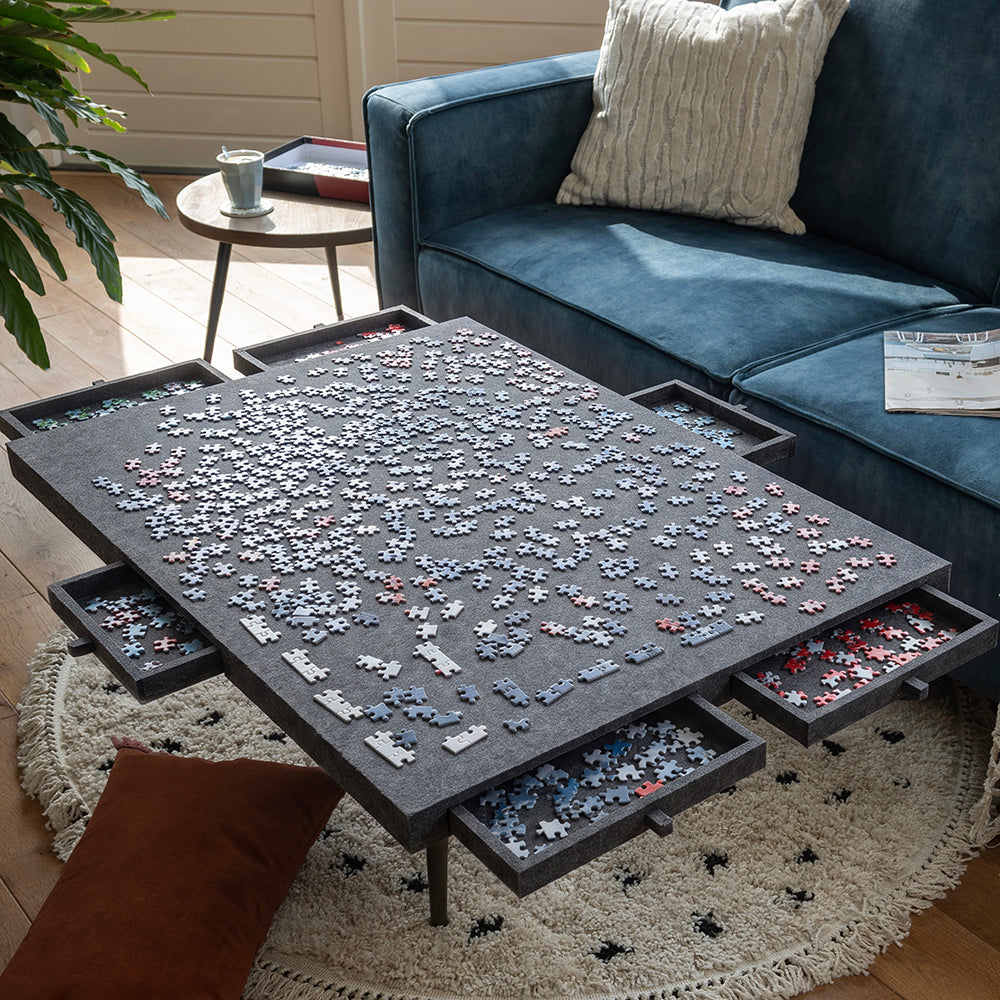 Plateau de puzzle en feutre sur une table basse, tiroirs ouverts remplis de pièces