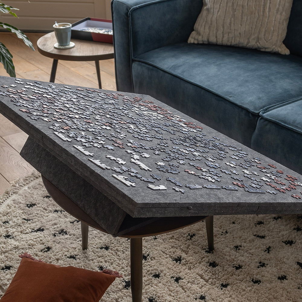 Grand plateau de puzzle en feutre en position inclinée sur une table basse devant le canapé