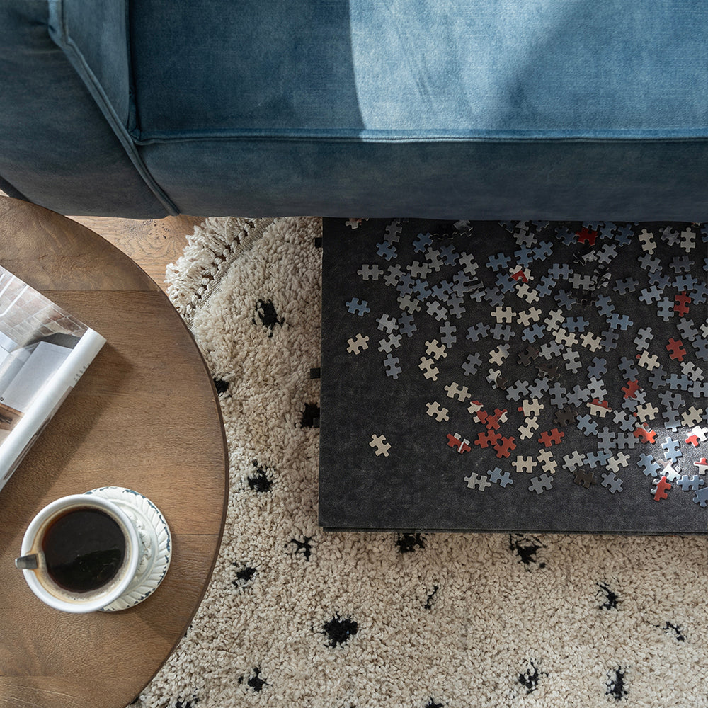 Grand plateau de puzzle en feutre avec des pièces, glissé en partie sous le canapé