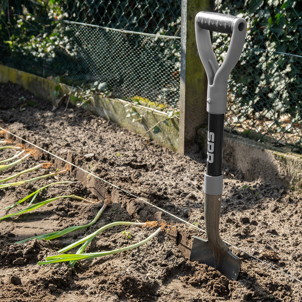 Bêche à poignée en D plantée dans la terre d'un potager
